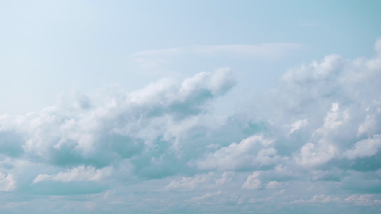 색 구름이 밝은 파란 하늘을 가로질러 떠다니며 평온함의 느낌을 불러일으킨다.