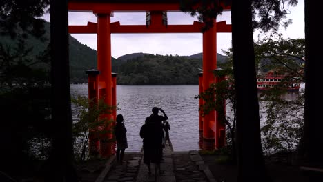 multitudes de turistas tomando fotografías en el santuario de hakone y el barco pirata que pasa en segundo plano