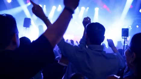 a crowd of people at a concert, raising their hands in the air, enjoying the music and lights.