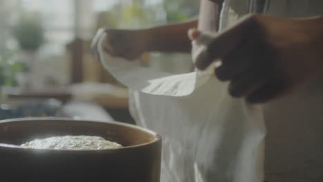 hands covering a bowl of dough with a cloth