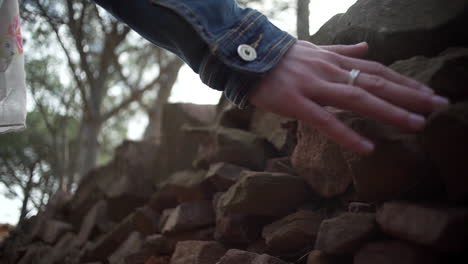 woman sliding hand against old ancient stone wall in slow motion. female hand touching hard rough surface of rock, valencia, spain
