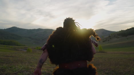 man wearing fur clothes with leather belt runs along valley