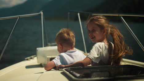 positive little boy and girl observe nature sailing on motorboat in sea on sunny day. brother and sister enjoy water trip sailing yacht in ocean on holiday