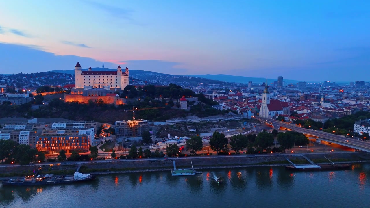 Castello di Bratislava e skyline del centro storico al crepuscolo. Veduta aerea panoramica del paesaggio urbano con cattedrale e fortezza illuminate sotto un cielo crepuscolare.