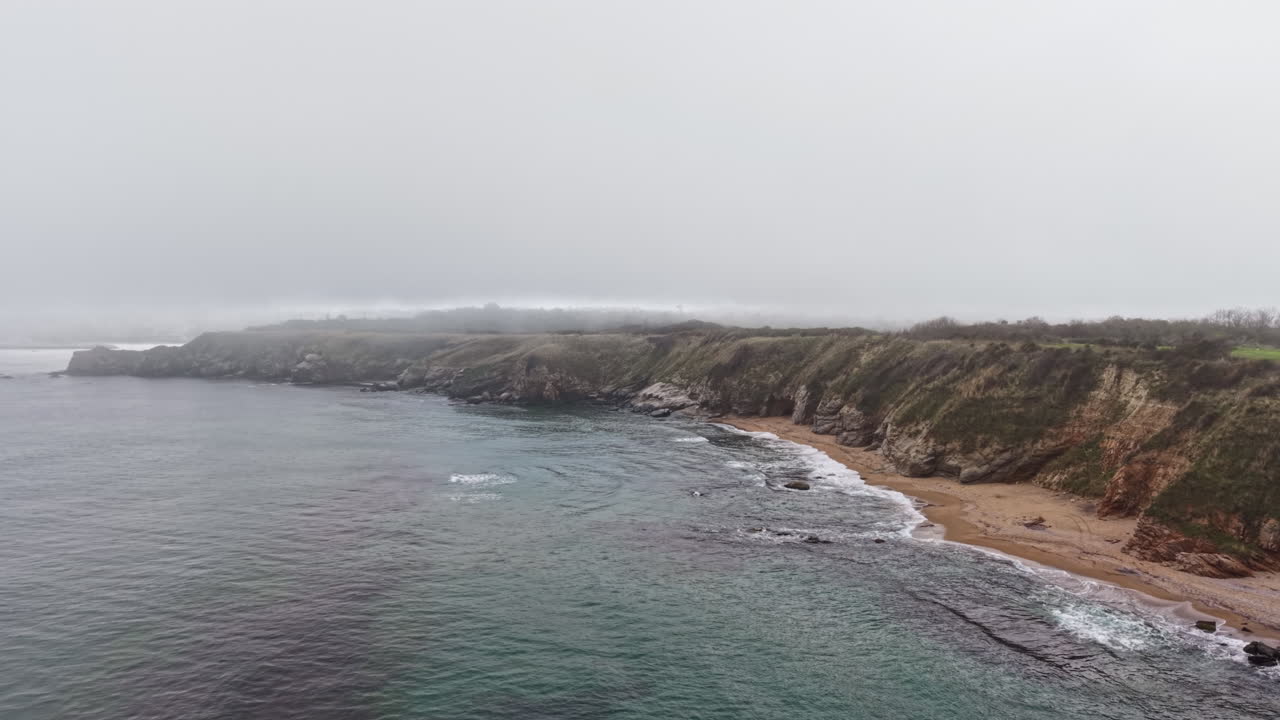 Mist envelops rocky coastline revealing a serene bay at dawn, inviting contemplation of nature's beauty and tranquility