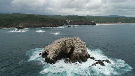 aerial drone shot of a big rock formation and the coastline of zipolite, oaxaca