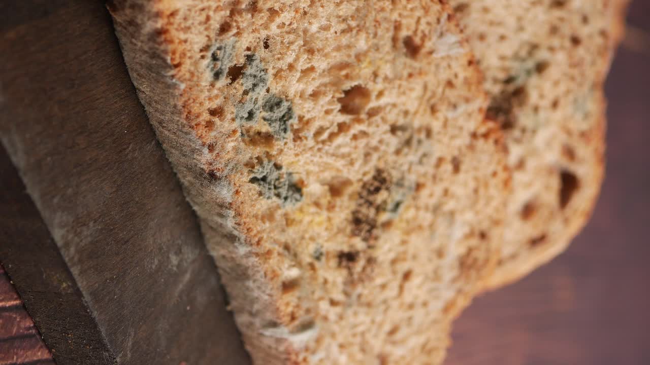 Primo piano di una fetta di pane ammuffito su una superficie di legno