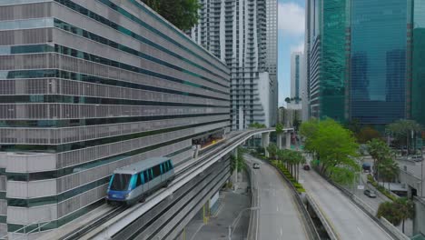 futuristic city borough with modern high rise buildings and automatic passenger transport rail vehicle. metromover stopping at station. miami, usa