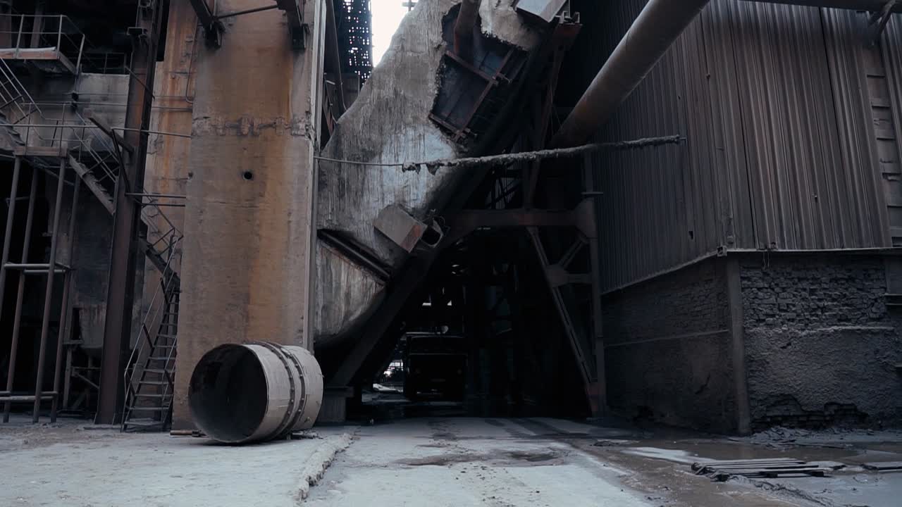 Truck moves through a tunnel in an old abandoned factory with rusty metal structures and pipes. Factory concrete walls