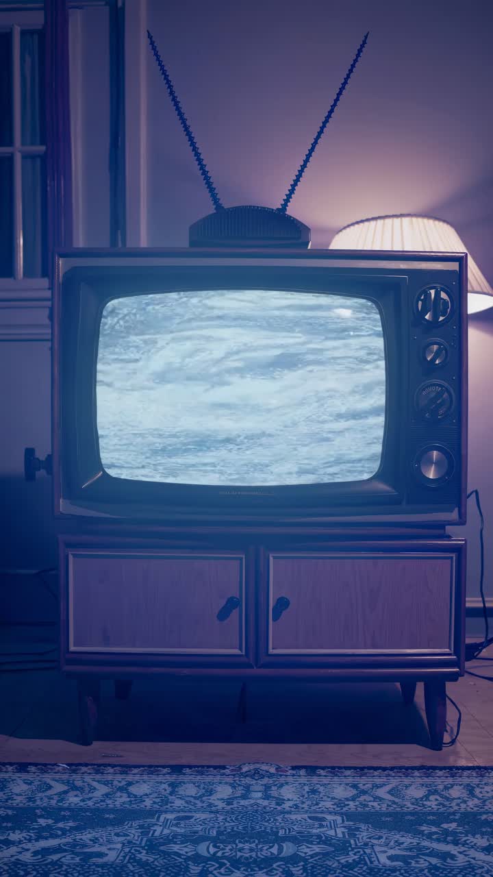 Vintage TV displaying static video in a dimly lit room. Shot from a low angle
