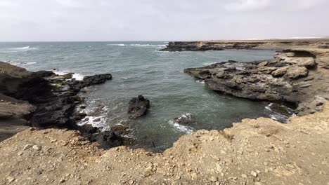 wide view of rugged, rocky coastline of turtle bay in boa vista, cape verde. captures the raw beauty of the shoreline with its jagged cliffs and clear waters, ideal for nature and seascape lovers