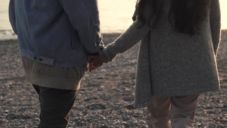 couple walking hand-in-hand on the beach at sunset