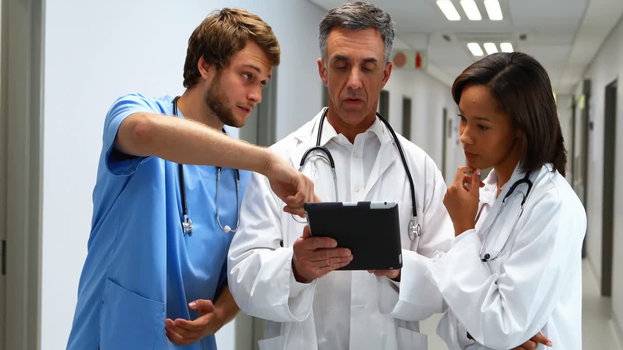 Doctors discussing over digital tablet in corridor