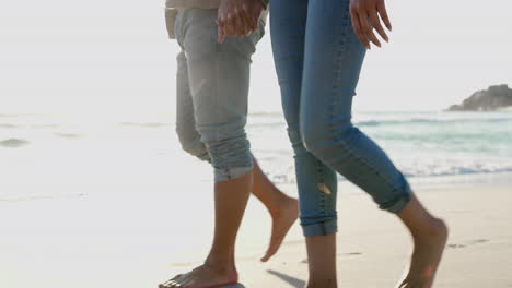 legs, holding hands and couple walking on beach