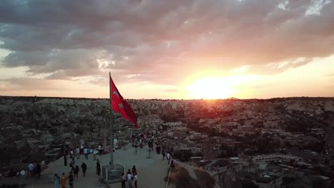 aerial view of sunset over cappadocia. turkish flag on viewpoint above city and rocky landscape