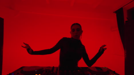 a female dj in a red lit nightclub