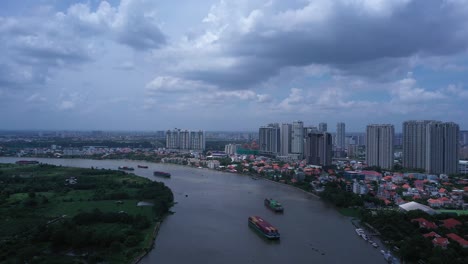 aerial panning shot of large river boats carrying shipping containers on the saigon river in ho chi minh city