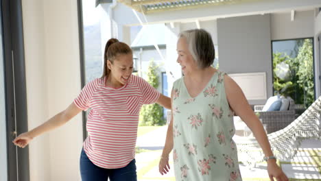 Asian-grandmother-and-biracial-granddaughter-dancing-inside