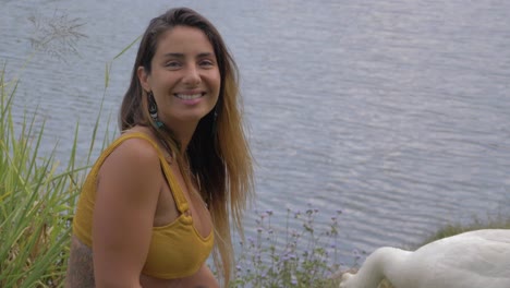 girl feed the goose by mouth with rippling water in the background - beautiful girl smiles as she looks at the camera after feeding goose - gold coast, qld, australia