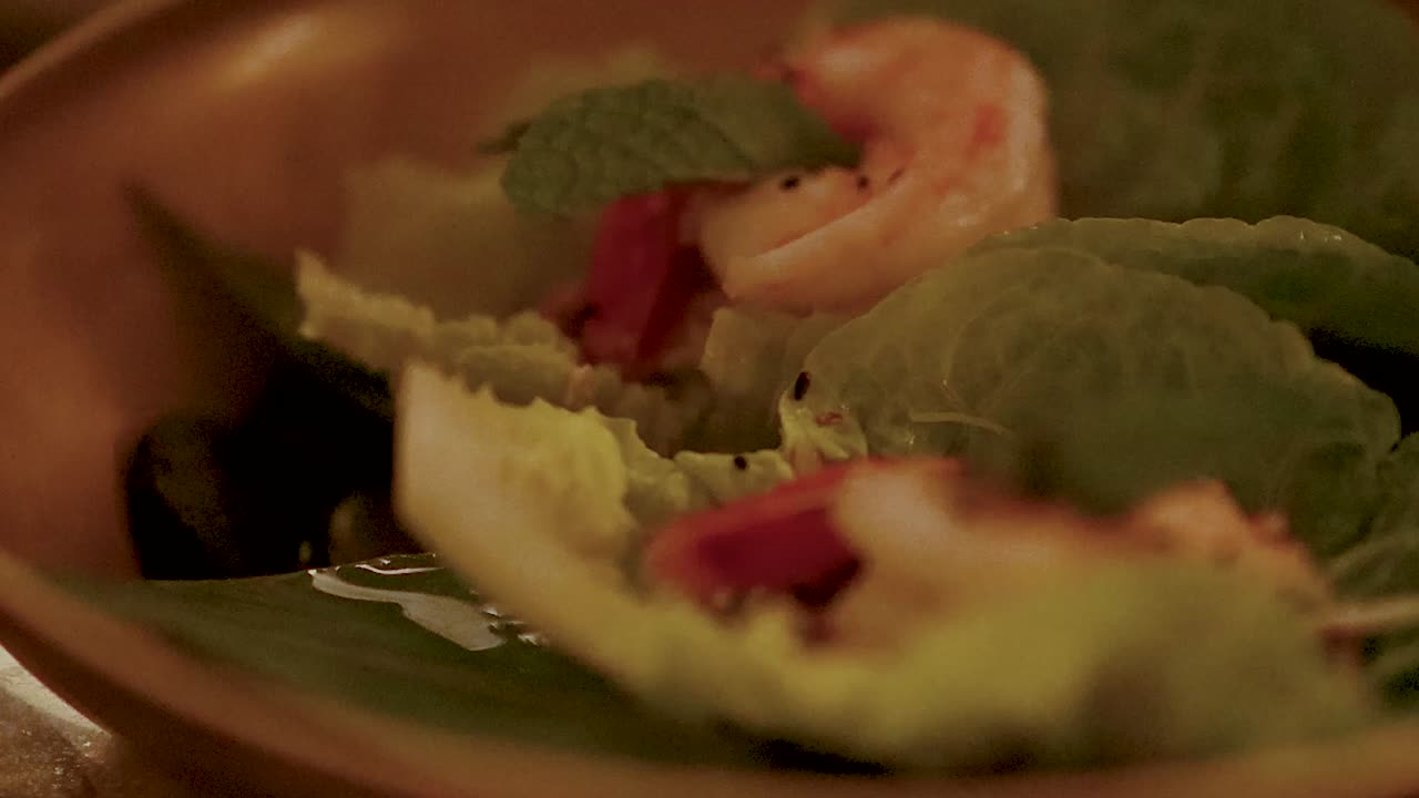 Macro shot of fresh shrimp and herbs served on lettuce leaves in a wooden bowl