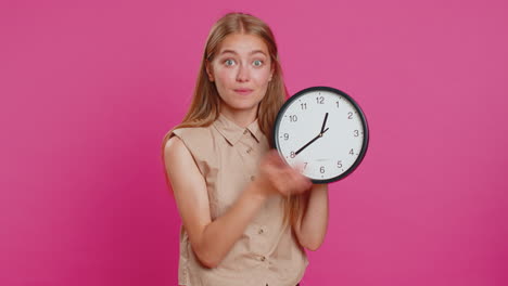 woman showing time on wall office clock, ok, thumb up, approve, pointing finger at camera, your time