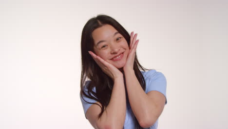 색 스튜디오 배경 앞의 젊은 여성이 사진 부스 스타일의 초상화를 위해 포즈를 취하고 있습니다.