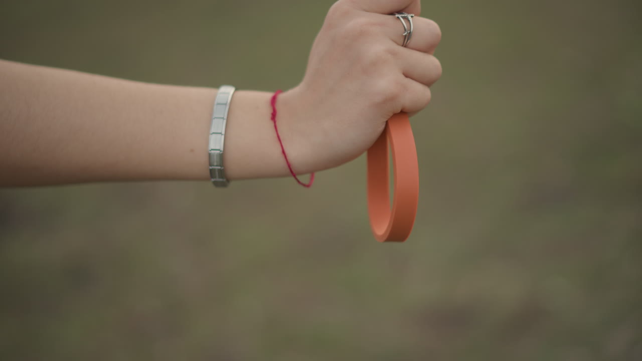 Close Hand Grip, Detailed Image Of Hand With Jewelry Gripping Bright Leash On Grassy Area, Closeup Shot Emphasizing Hand With Jewelry Firmly Grasping Leash Above Grassy Terrain In Detail