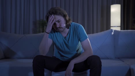 Depressed-and-worried-young-man-sitting-alone-on-sofa-at-home.