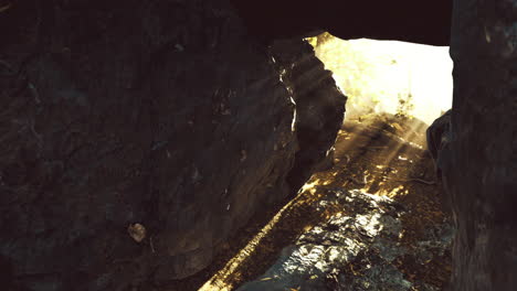 Sunlight streaming through rocky cave entrance during bright midday hours
