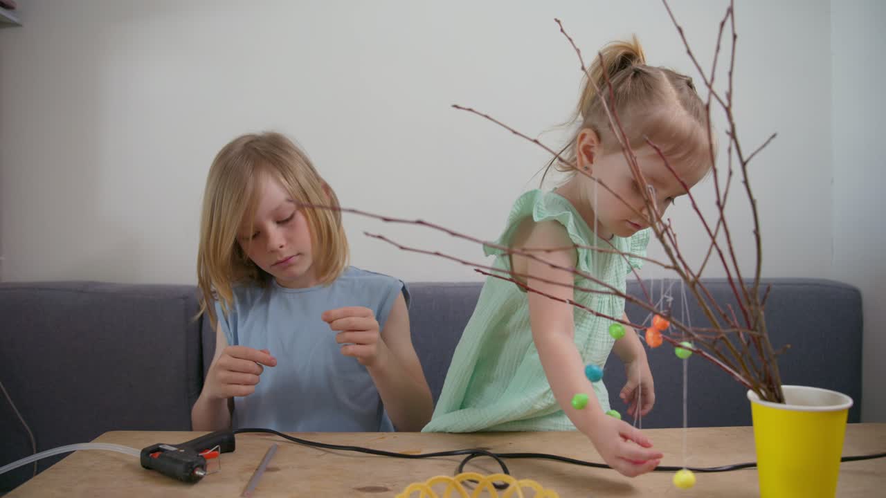 Two Young Girls Decorating Easter Branches with Colorful Ornaments