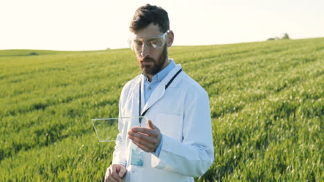 Investigador-Caucásico-Con-Bata-Blanca-Y-Gafas-Golpeando-El-Vidrio-En-El-Campo-Verde