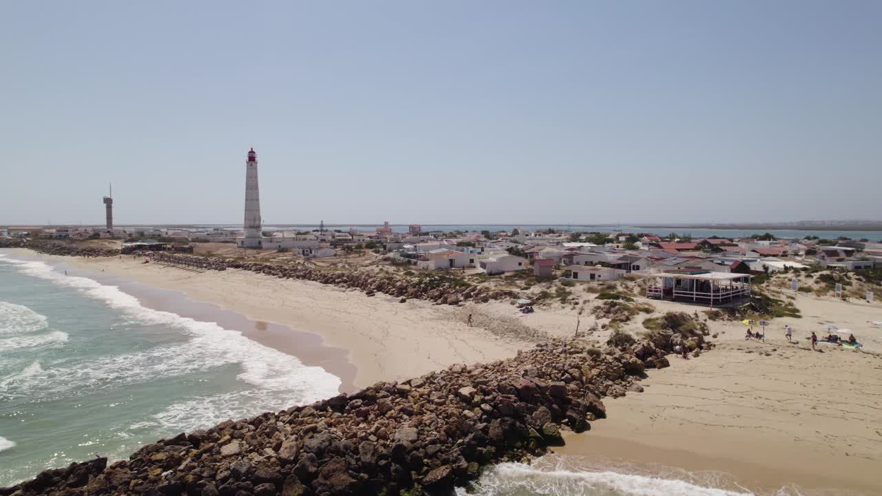 vista aérea de la isla de farol, olhão, portugal, con una playa, un faro y una ciudad costera