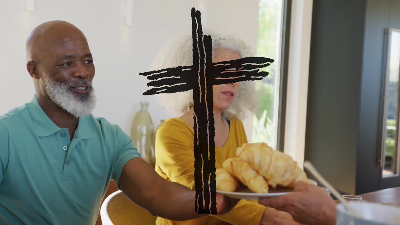 Elderly couple sharing croissants at home with cross animation overlay