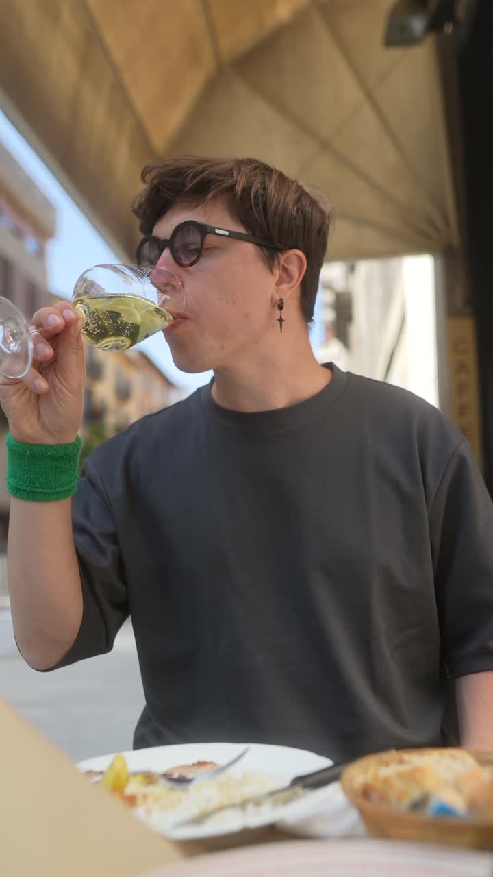 Man enjoying a drink and meal outdoors in a city cafe.