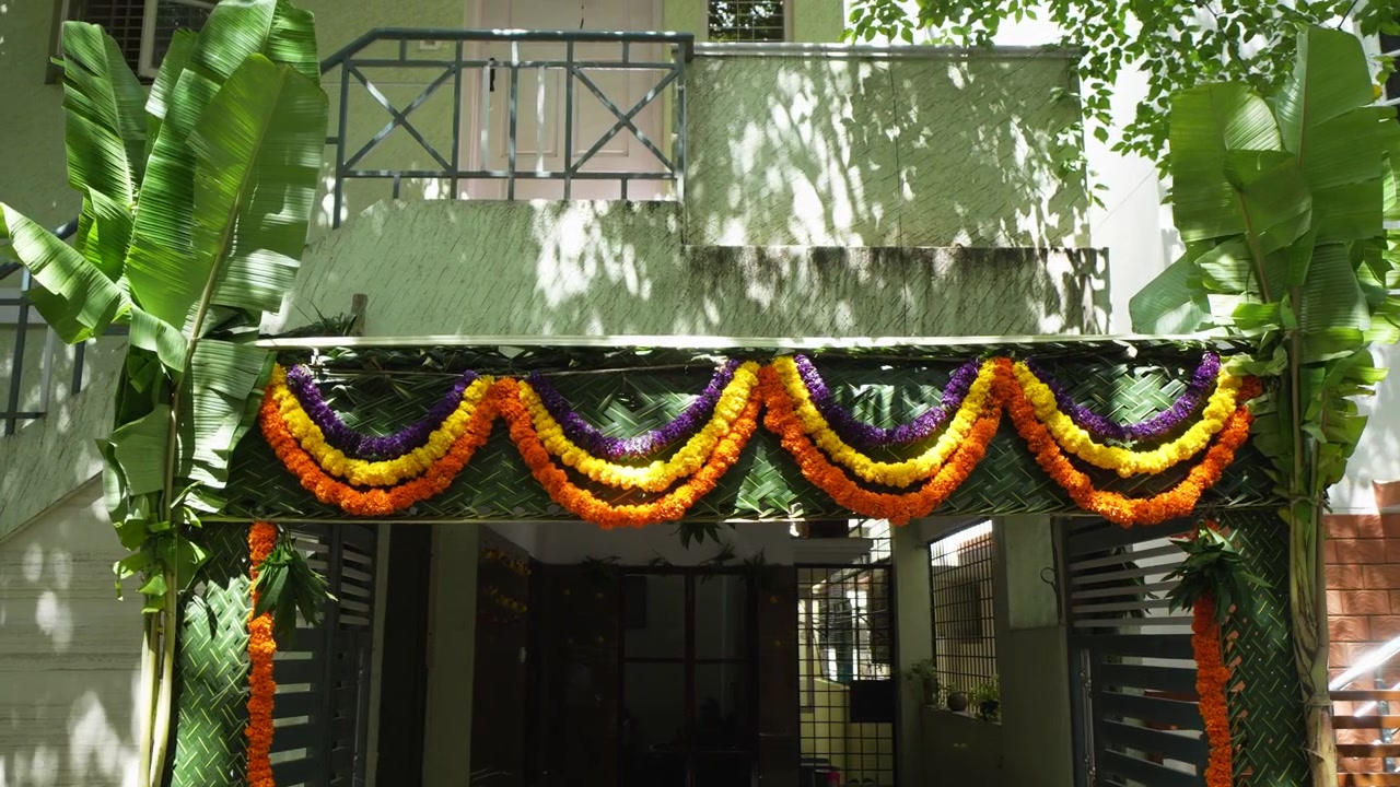 Ingresso nuziale chapra colorato con alberi di banane e ghirlande di calendule fuori da una casa dell'India meridionale in piena luce del giorno.