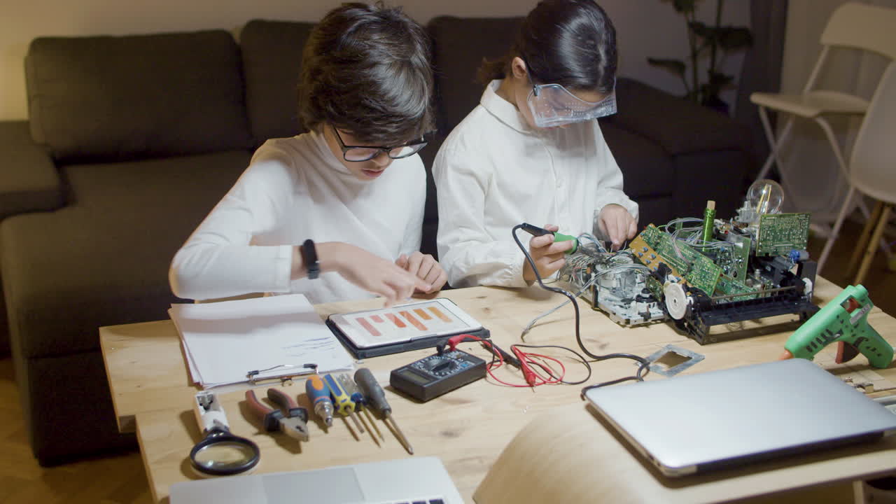 Two smart children sitting at desk and doing project work