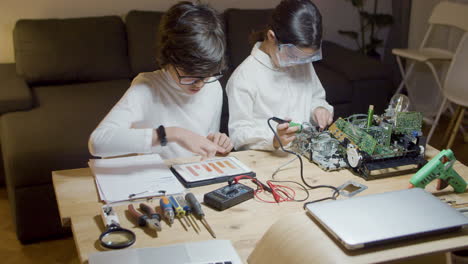 dos niños inteligentes sentados en el escritorio y haciendo trabajo de proyecto