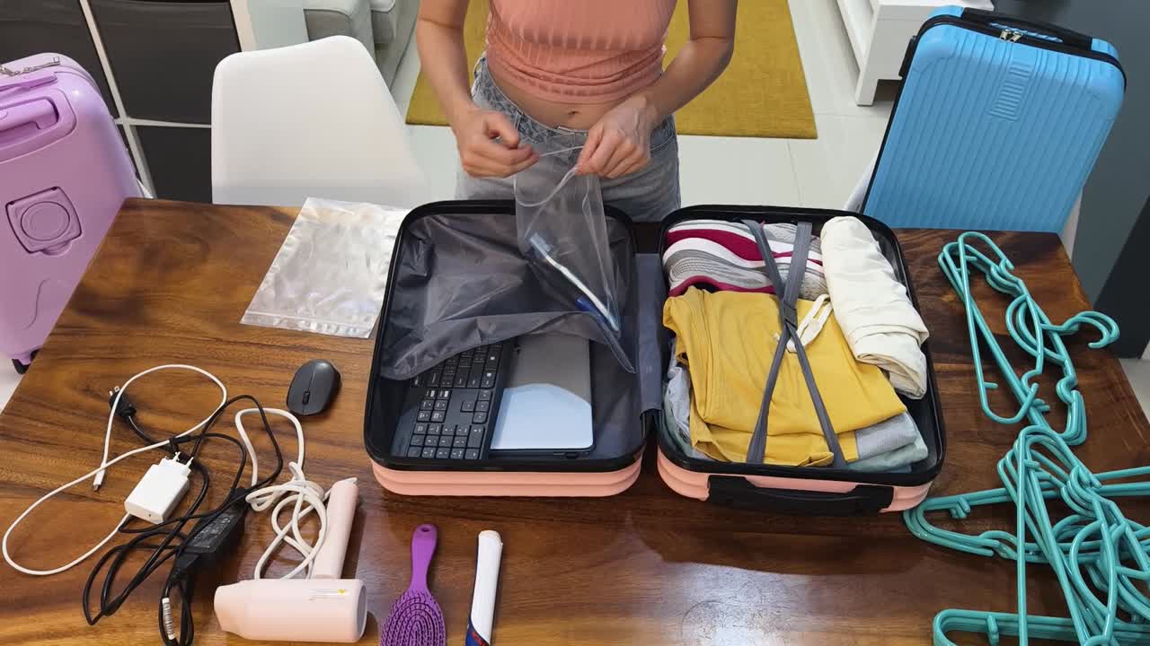 Woman packing suitcase with clothes and electronics