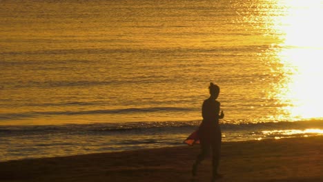 woman-jogging-on-sandy-beach-at-sunrise,-slow-motion