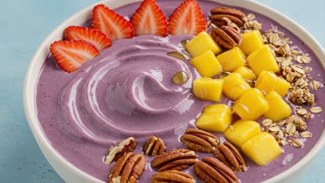 deliciously smooth berry and mango yogurt bowl topped with fresh strawberries, crunchy pecans, and oats for a healthy breakfast or snack option