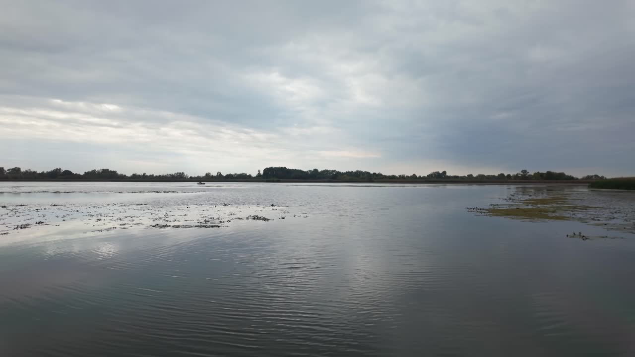 Gloomy landscape of Lake Tisza as dark clouds reflect off the water surface on an autumn day in Hungary
