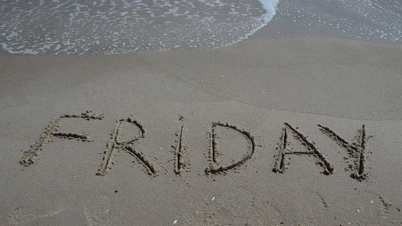 Indskrift FREDAG på blødt strandsand med den blide bølge. Optagelse på stranden