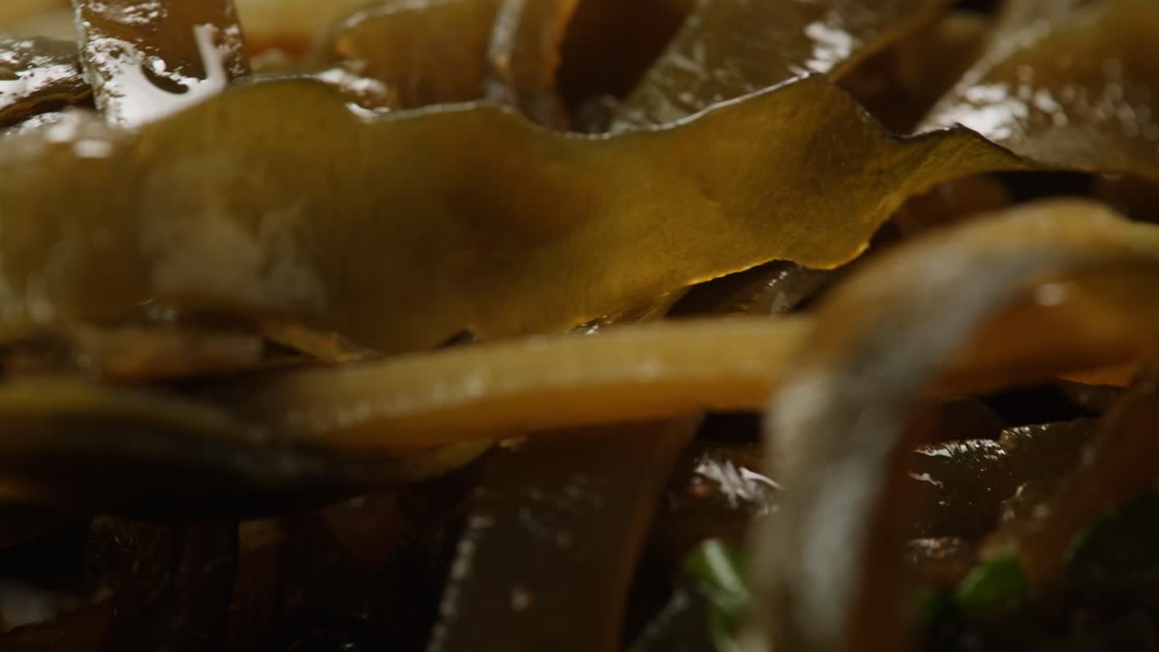 Japanese wakame sea weed laminaria chuka fermented food. Close-up on a detail of Hiyashi Wakame Chuka or seaweed salad or seaweed with sesame seeds on a plate. Top view. Seafood background.