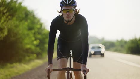 Male-cyclist-in-helmet-rides-bicycle-along-the-track,-gaining-speed