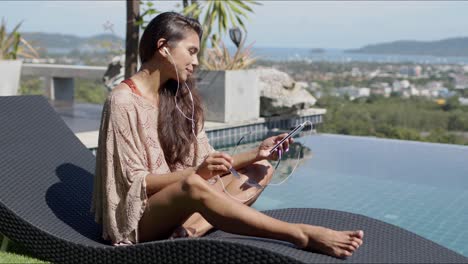 relaxed woman with smartphone listening to music at poolside