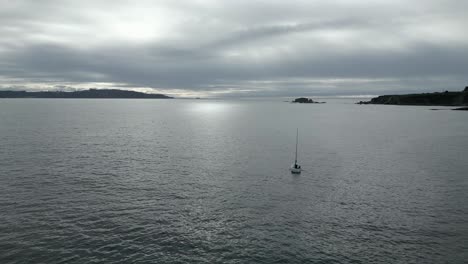 Aerial-flying-over-sailboat-sailing-in-calm-waters-on-cloudy-day,-Ares,-Spain