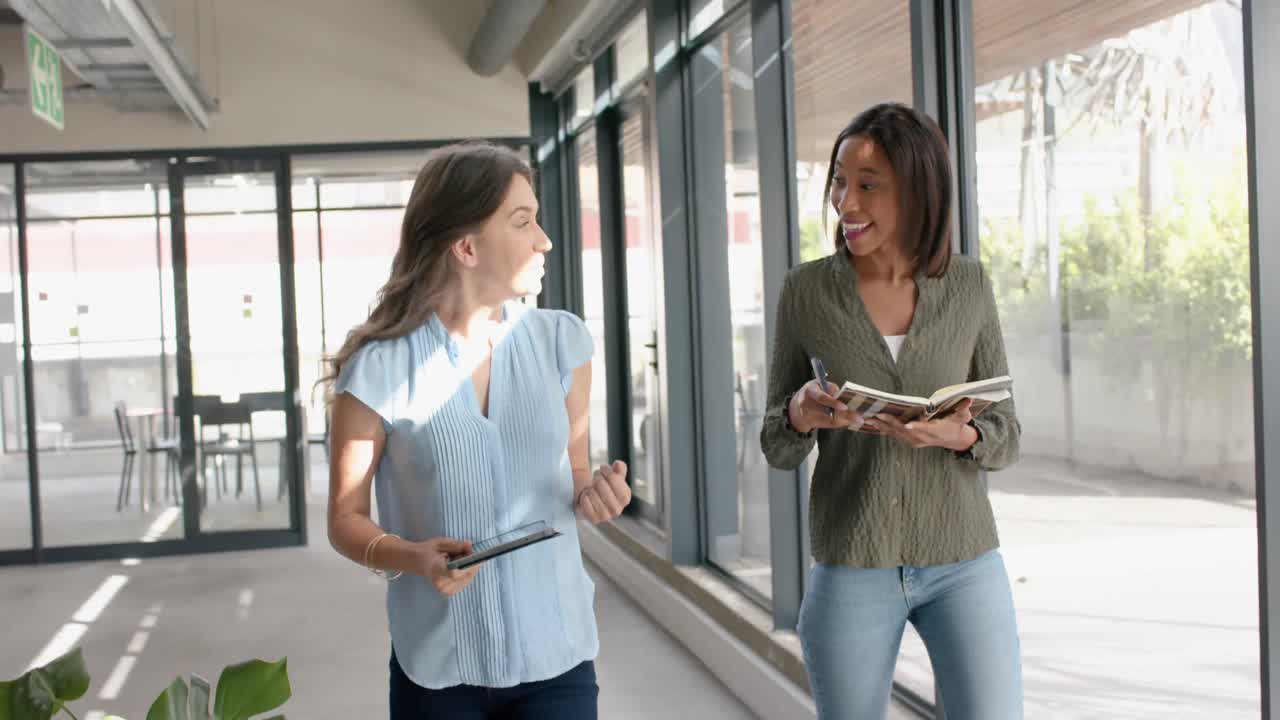 dos mujeres de negocios diversas discutiendo entre sí mientras caminan en la oficina