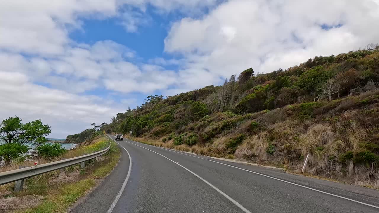 A 14-second video captures a drive along the Great Ocean Road, showcasing coastal views and lush greenery under a partly cloudy sky