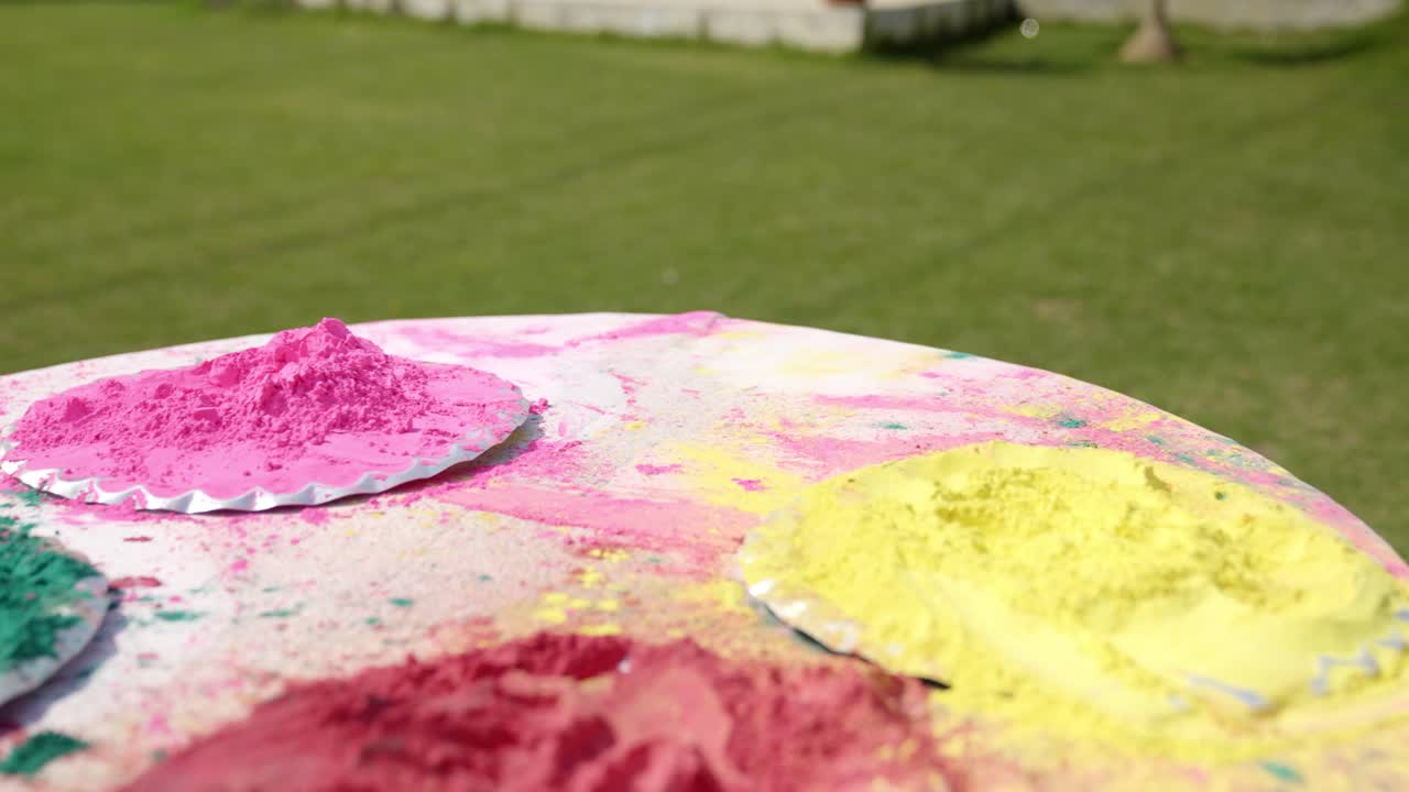 Uomo indiano che raccoglie colore gulal rosa da un piatto