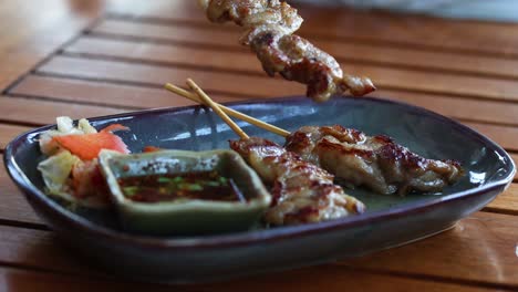 grilled skewers being placed on a plate